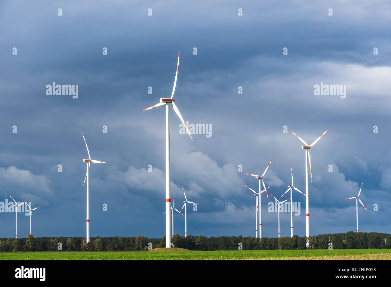 Windturbinen im offenen Gelände an windigen Tagen mit dunklen Wolken am Himmel. Alternative Stromerzeugung. Stockfoto