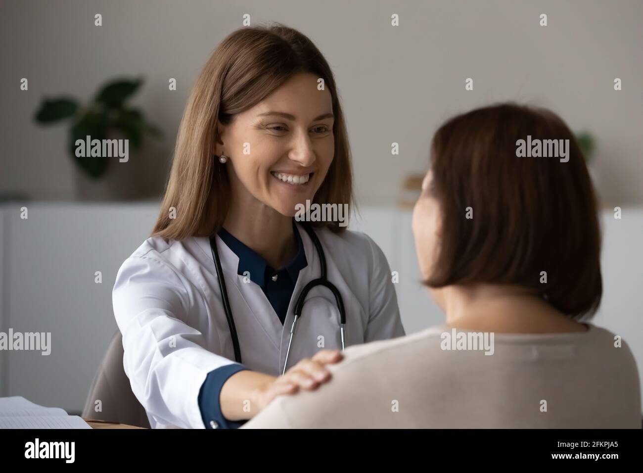 Lächelnde Ärztin unterstützt ältere Patienten beim Treffen Stockfoto