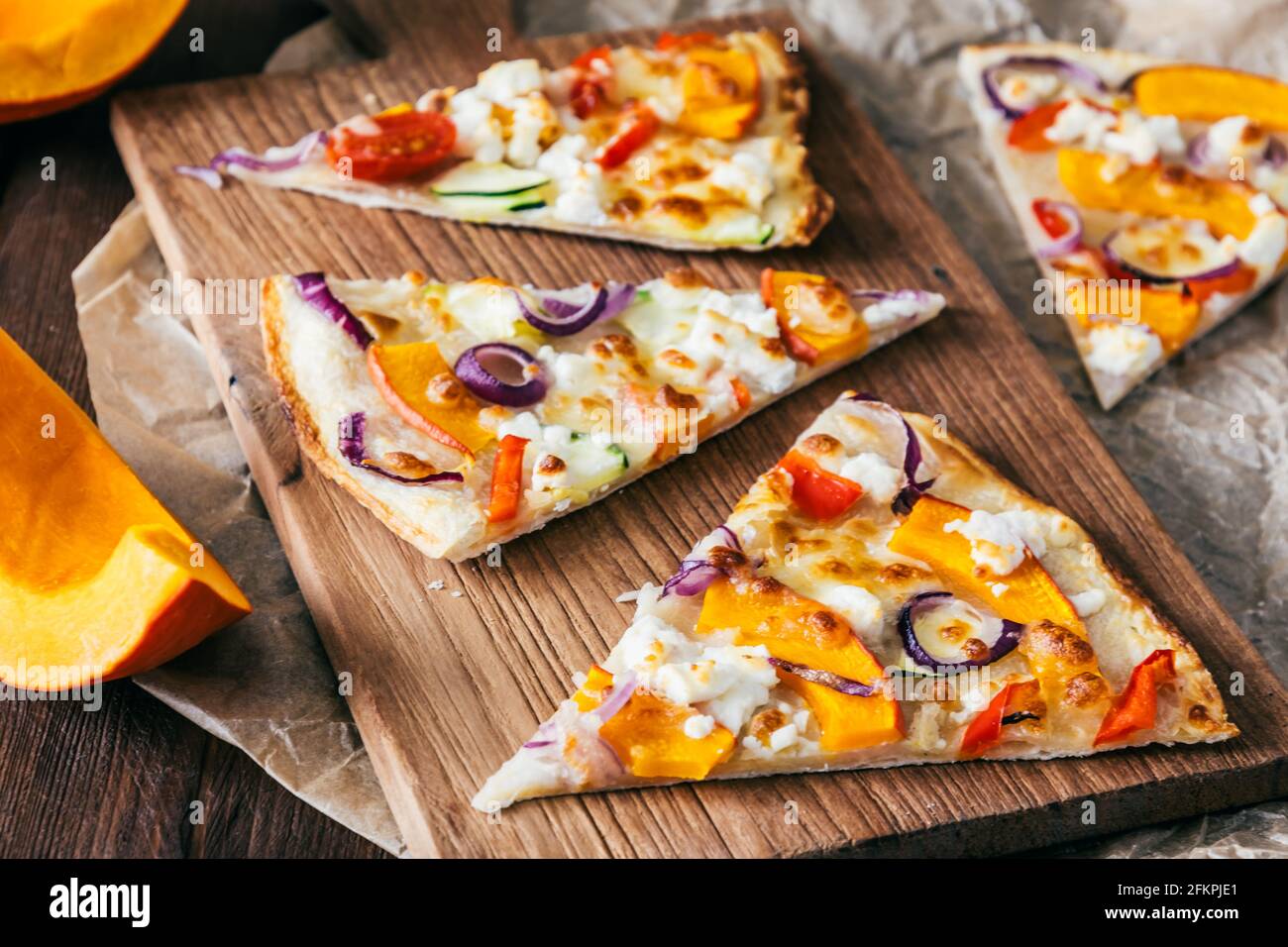 Flambienstücke mit Kürbis, roten Zwiebeln und Käse auf einem Holzbrett Stockfoto