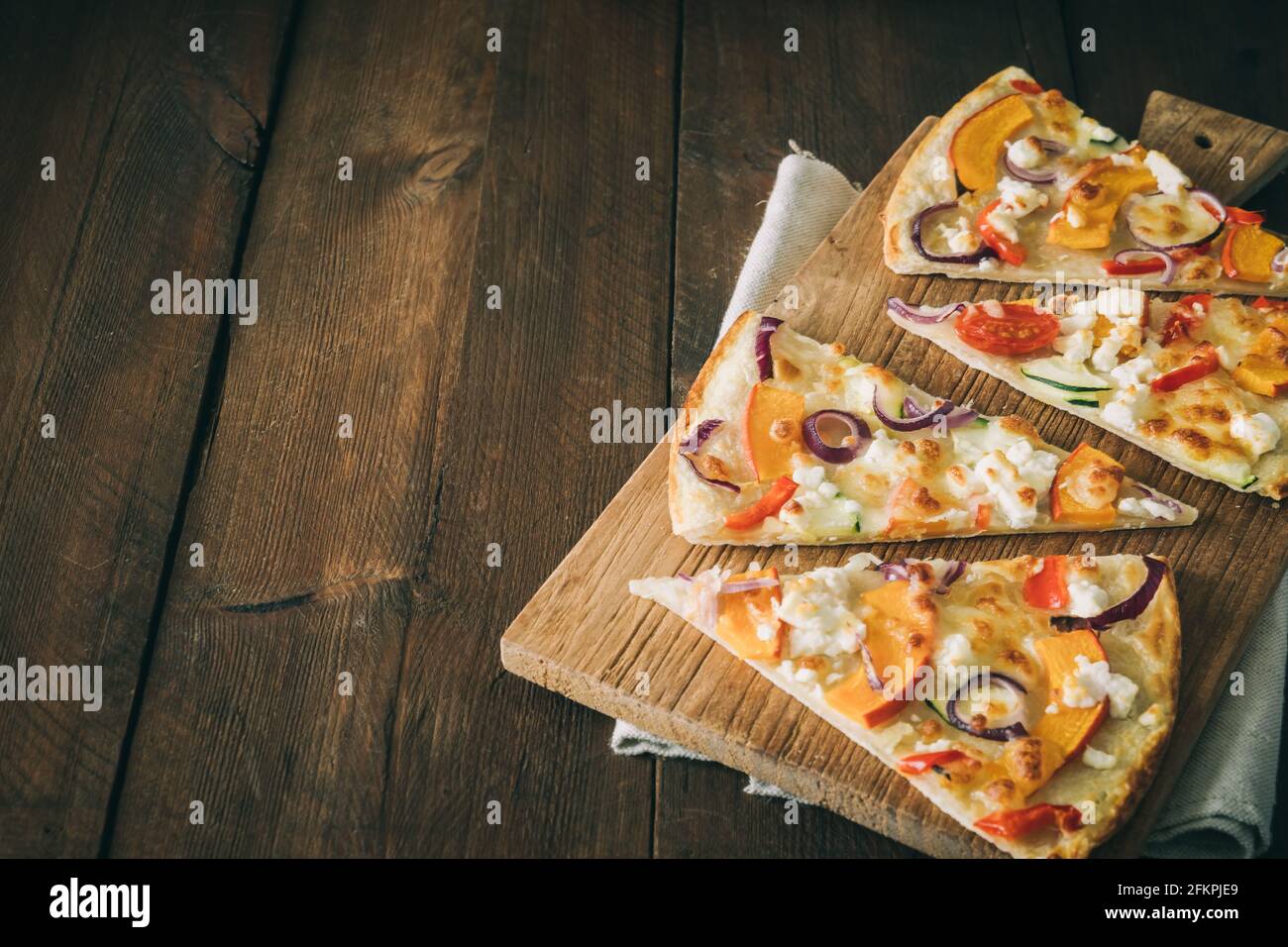 Flammenstücke mit Kürbis, roten Zwiebeln und Käse auf einem rustikalen Holztisch mit Kopierfläche Stockfoto