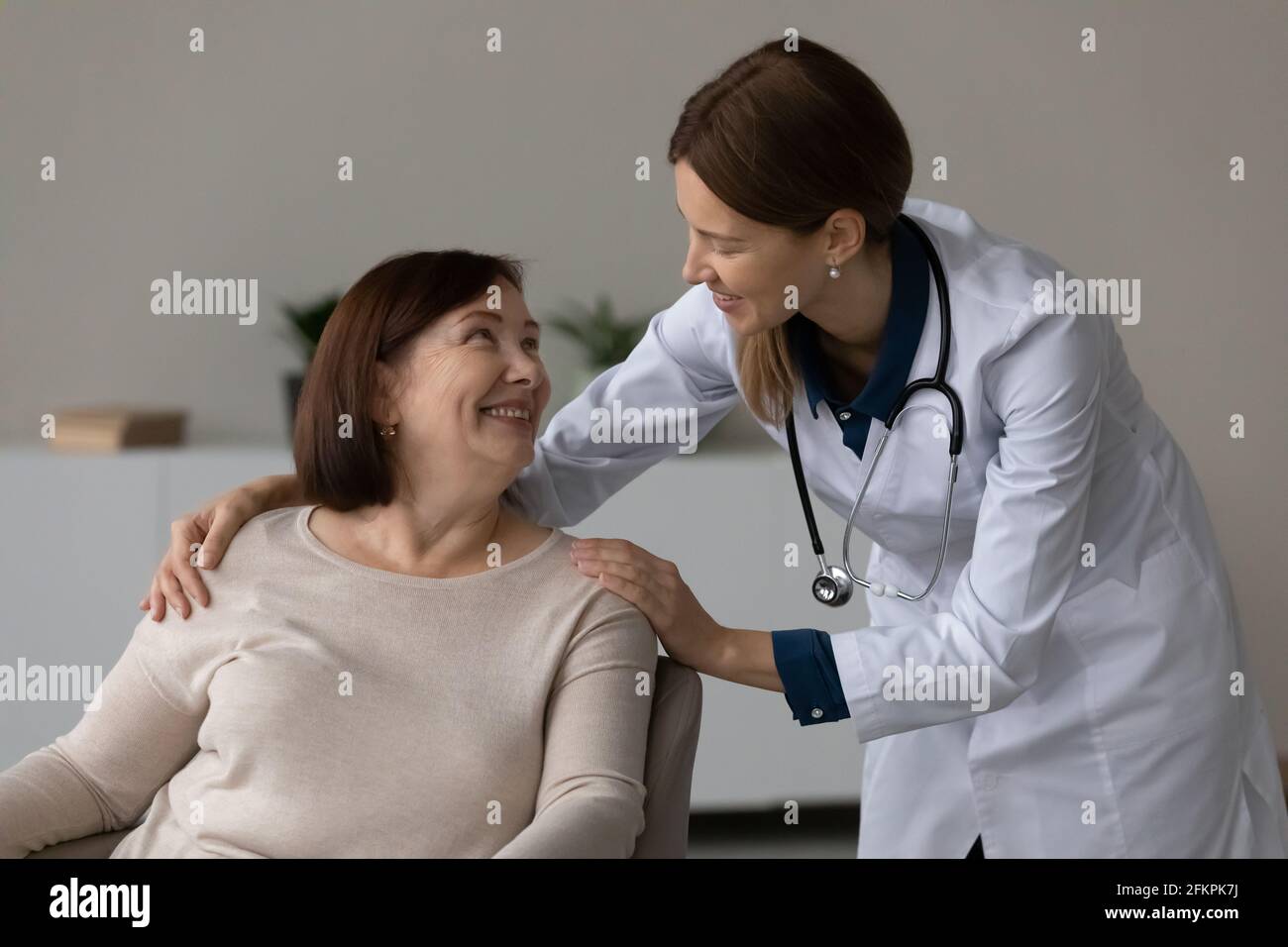 Lächelnde Krankenschwester tröstet ältere Patienten im Krankenhaus Stockfoto