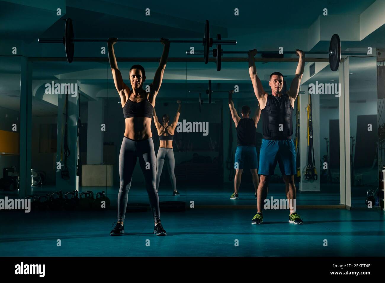 Ein Workout-Paar Training im Fitnessstudio und tun Overhead hockt Übung mit Gewicht auf der Langhantel. Stockfoto