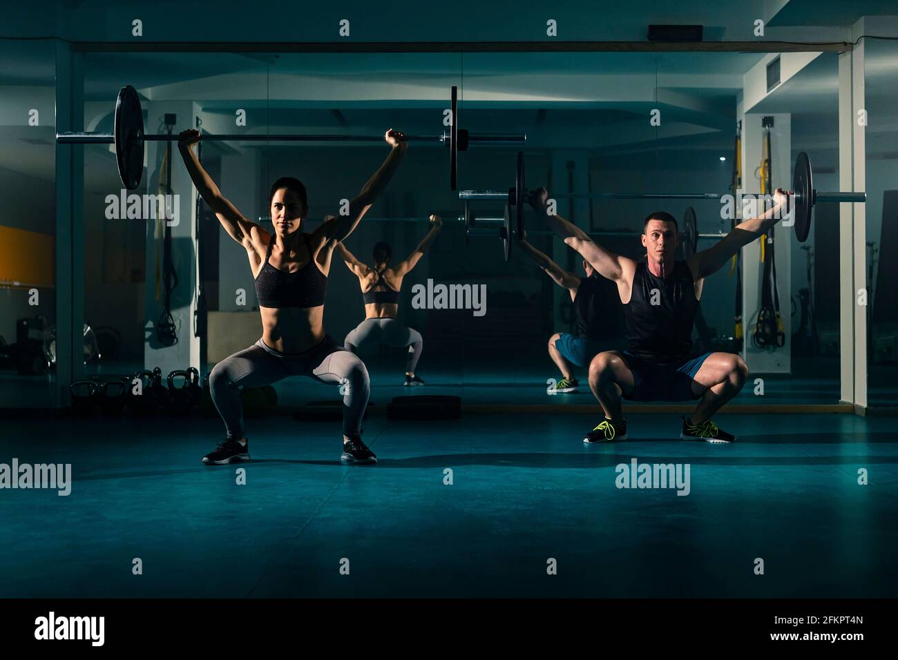 Ein Workout-Paar Training im Fitnessstudio und tun Overhead hockt Übung mit Gewicht auf der Langhantel. Stockfoto