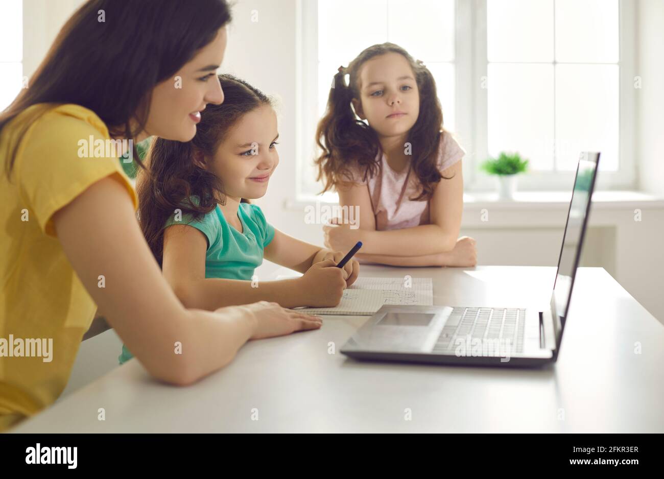 Glücklich lächelnde Mutter und Kinder, die zu Hause über den Laptop lernen Nehmen Sie an einem Online-Kurs statt Stockfoto