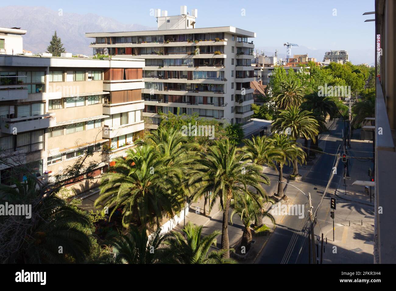 Apartment Gebäude Blick von der Terrasse mit Palmen in der Mitte der Straße und Los Andes Bergkette im Hintergrund. Wohnviertel Stockfoto