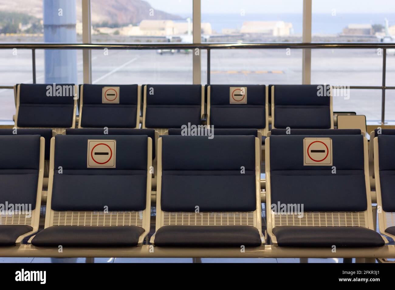 Leere Sitzplätze am Flughafenterminal ohne Sitzaufkleber aufgrund von Einschränkungen für die soziale Distanz bei Covid-19. Coronavirus-Pandemiefolgenkonzept Stockfoto