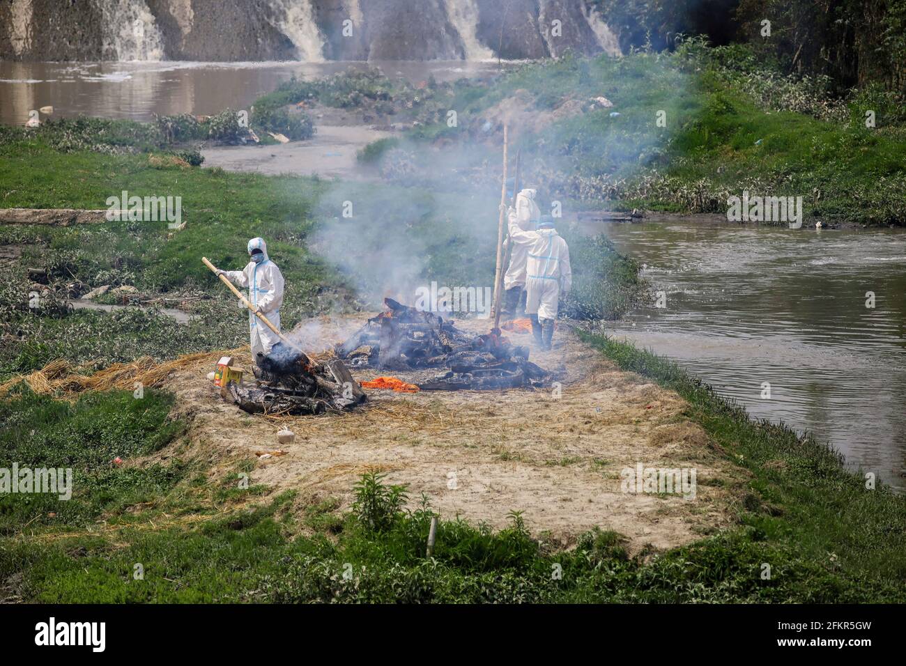 Kathmandu, Nepal. Mai 2021. Nepalesische Männer werden mit persönlicher Schutzausrüstung (PSA) gesehen und äschern die Leichen eines COVID-19-Opfers am Ufer des Bagmati-Flusses ein. Die nepalesische Regierung Verbot alle nationalen und internationalen Flüge bis zum 14. Mai 2021, da die Zahl der COVID-19-Fälle im Land weiter ansteigt. Kredit: SOPA Images Limited/Alamy Live Nachrichten Stockfoto