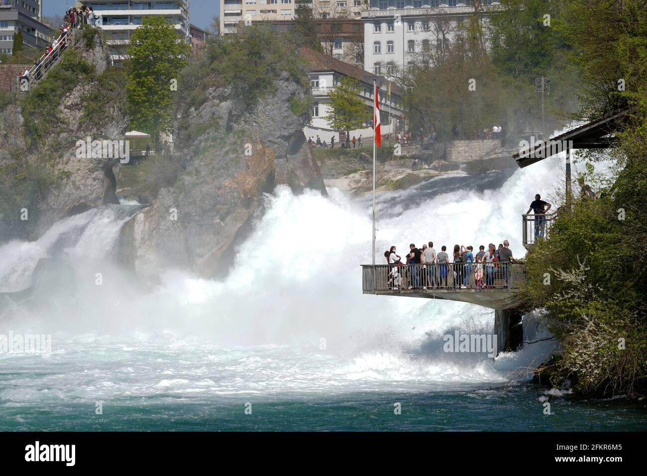 Touristen stehen auf einer hängenden Plattform und beobachten, wie schäumendes weißes Wasser in hoher Lautstärke und Geschwindigkeit herunterfällt. Stockfoto