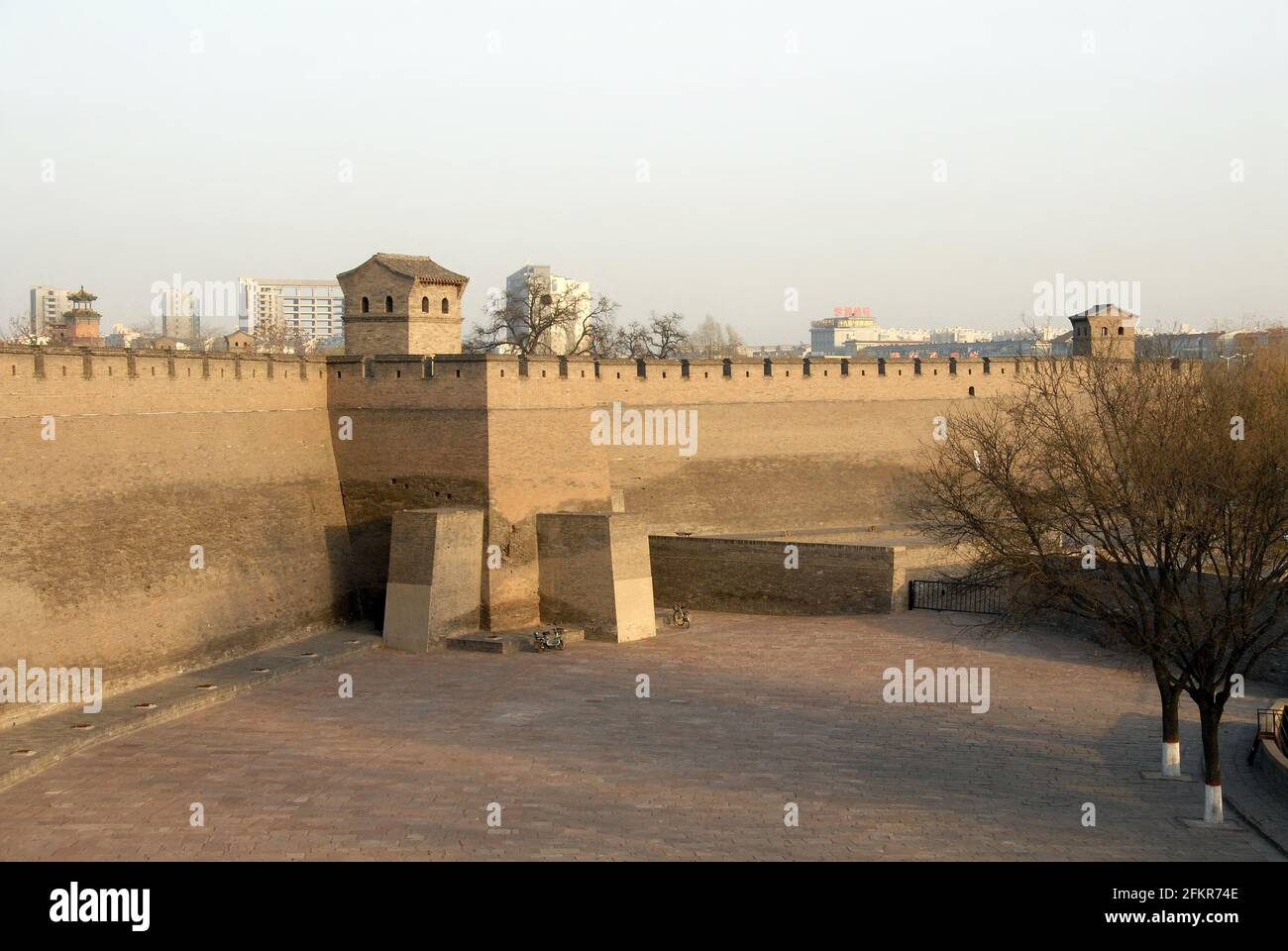 Pingyao in der Provinz Shanxi, China. Pingyao Stadtmauer in der späten Nachmittagssonne mit der modernen Stadt dahinter. Stockfoto