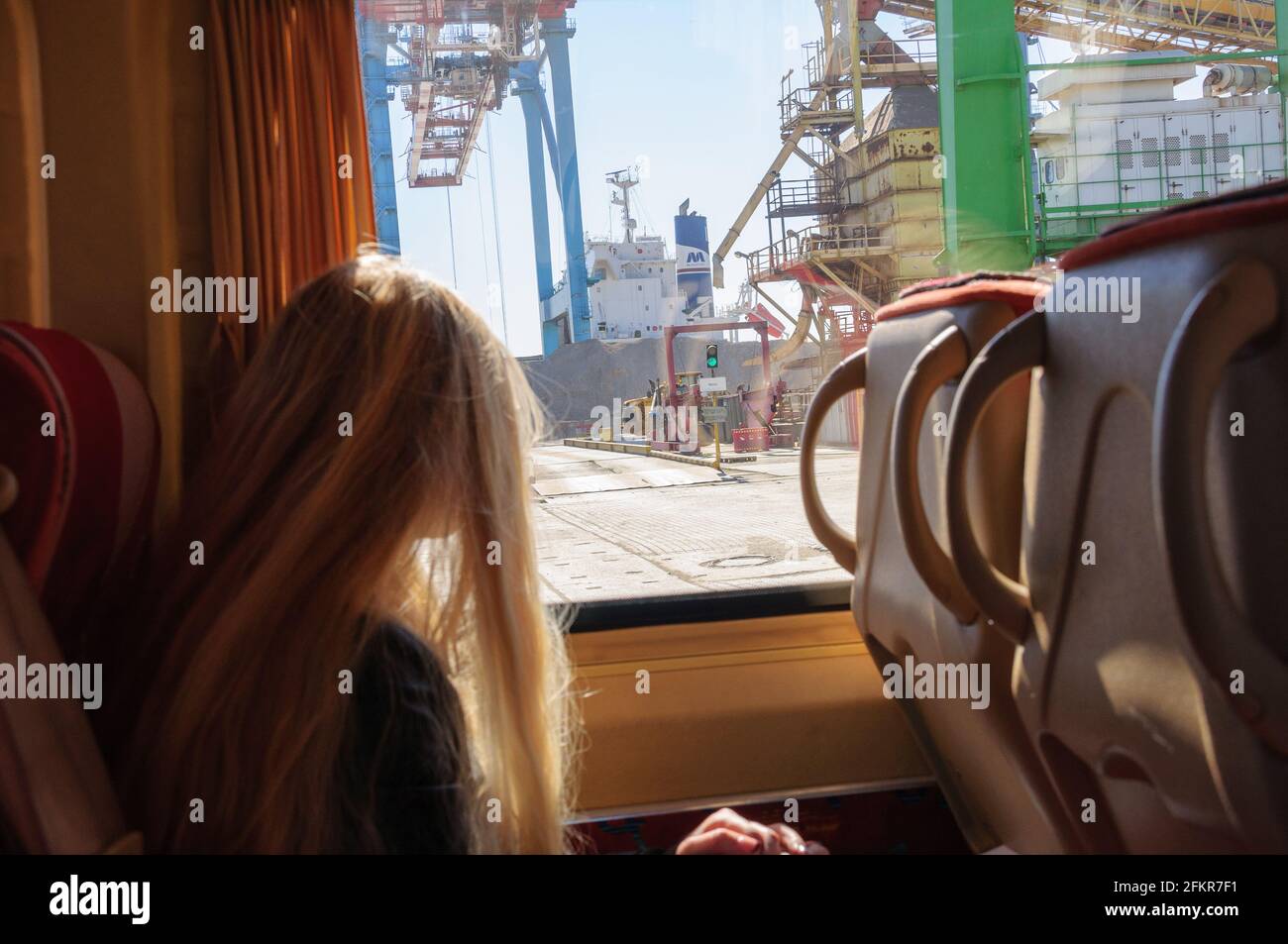 Frachthafen durch Fenster des Touristenbusses. Blick auf den Containerterminal vom Ausflugsbus mit verschwommener weiblicher Silhouette und entkokelten langen blonden hai Stockfoto