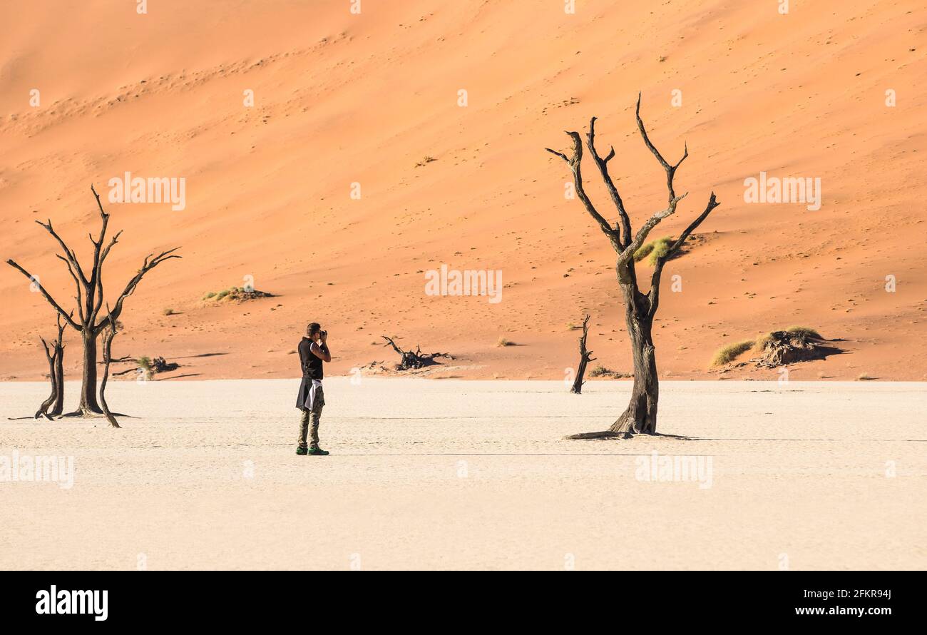 Einsamer Abenteuerreisenfotograf am Deadvlei-Krater im Sossusvlei-Gebiet - Namibian world famous Desert - Wanderkonzept mit african Natur Stockfoto