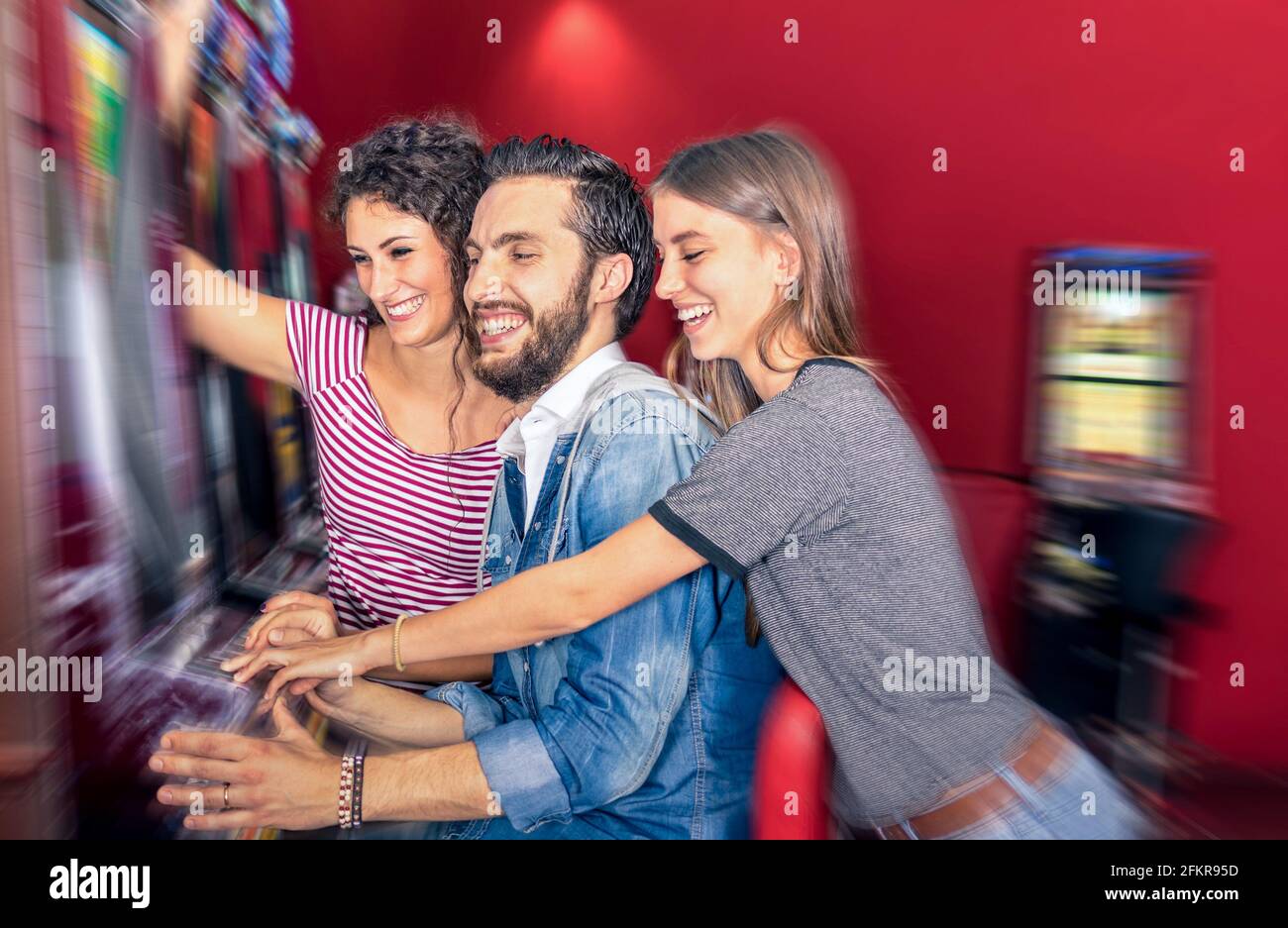 Glückliche junge Freunde, die zusammen mit Spielautomaten Spaß haben - Glücksspiel-Konzept mit Menschen spielen an Bargeld automatische Geräte in Modernes Casino und Resort Stockfoto