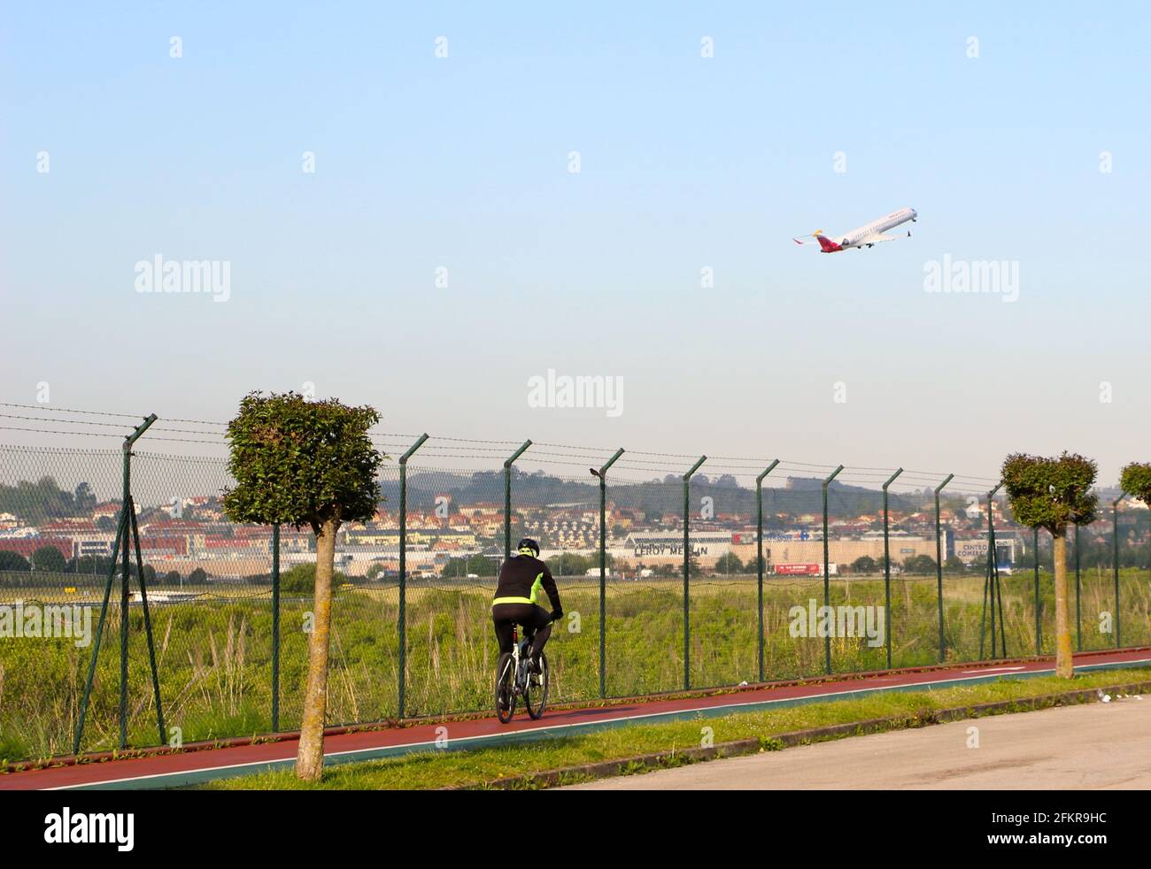 Ein Iberia-Passagierjet hebt vom Flughafen Santander ab, der nach Madrid fährt, und blickt vom Umzäunungszaun aus mit einem Radfahrer, der an Spanien vorbeifährt Stockfoto