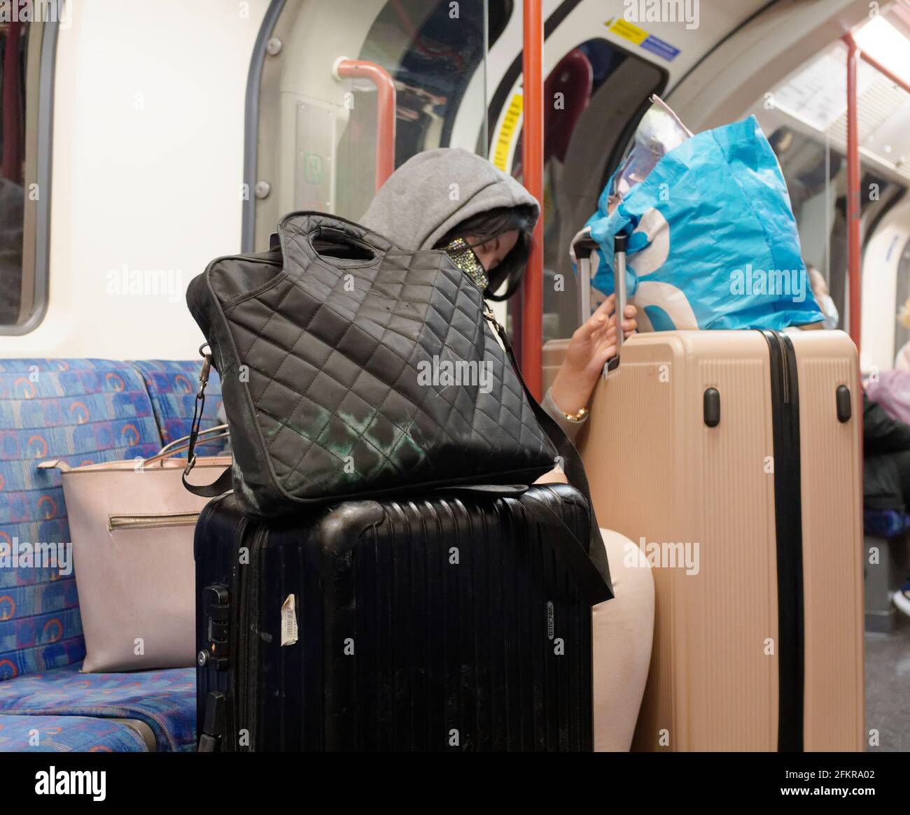 London, Greater London, England - 27 2021. April: Eine einreisende Person in der U-Bahn hält sich an ihr überflüssiges Gepäck fest. Stockfoto