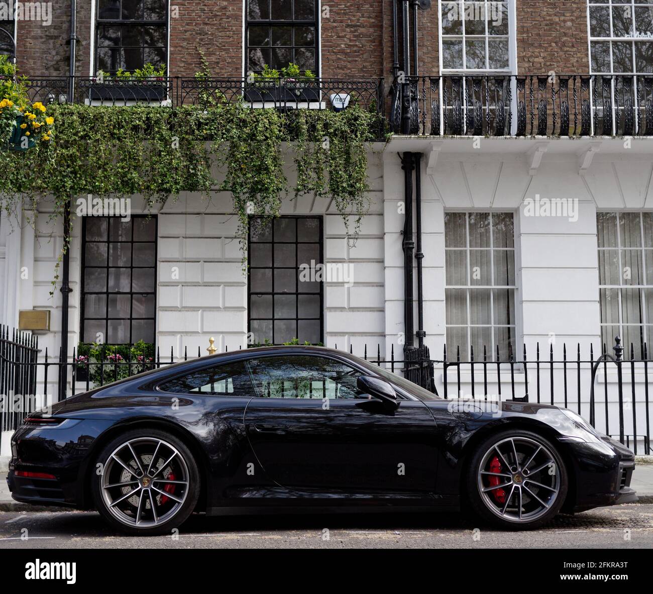 London, Greater London, England - 27 2021. Apr: Schwarzer Porsche parkte vor einer Wohnimmobilie mit Geländern. Stockfoto