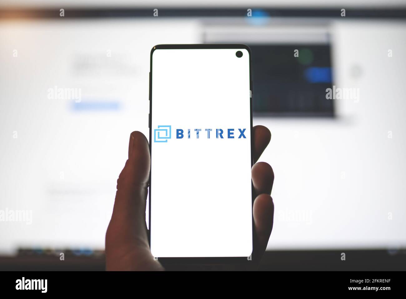 SWANSEA, Großbritannien - 1. MAI 2021: Mann mit Smartphone und Bittrex-App-Logo mit verschwommenem Website-Hintergrund. Kryptowährungsbörse, Handelsplattform Stockfoto