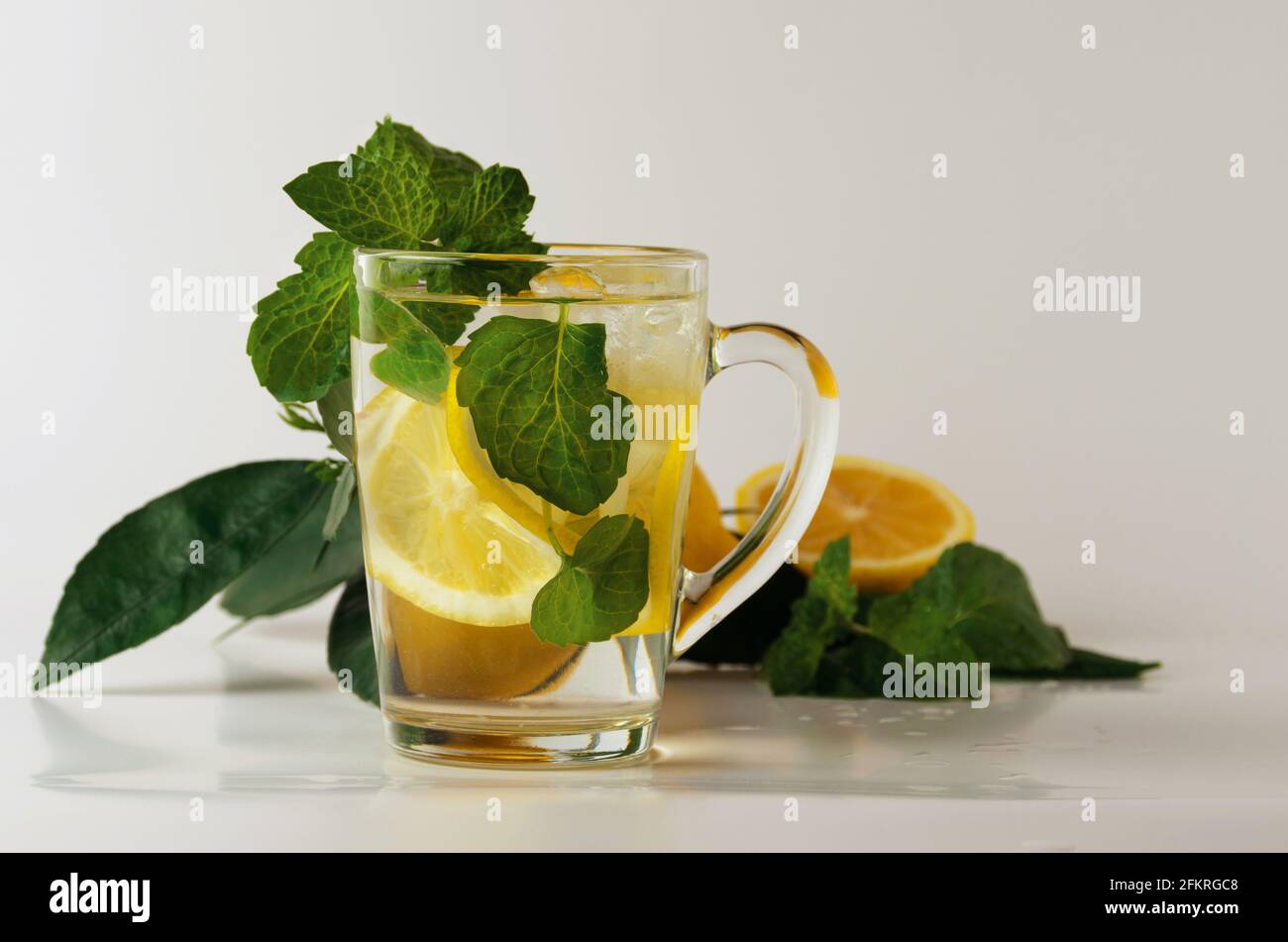 Erfrischende Limonade. Ein Glas Wasser mit Zitronenscheiben, Minzblättern und Eiswürfeln. Alkoholfreies gekühltes Getränk. Selektiver Fokus. Stockfoto
