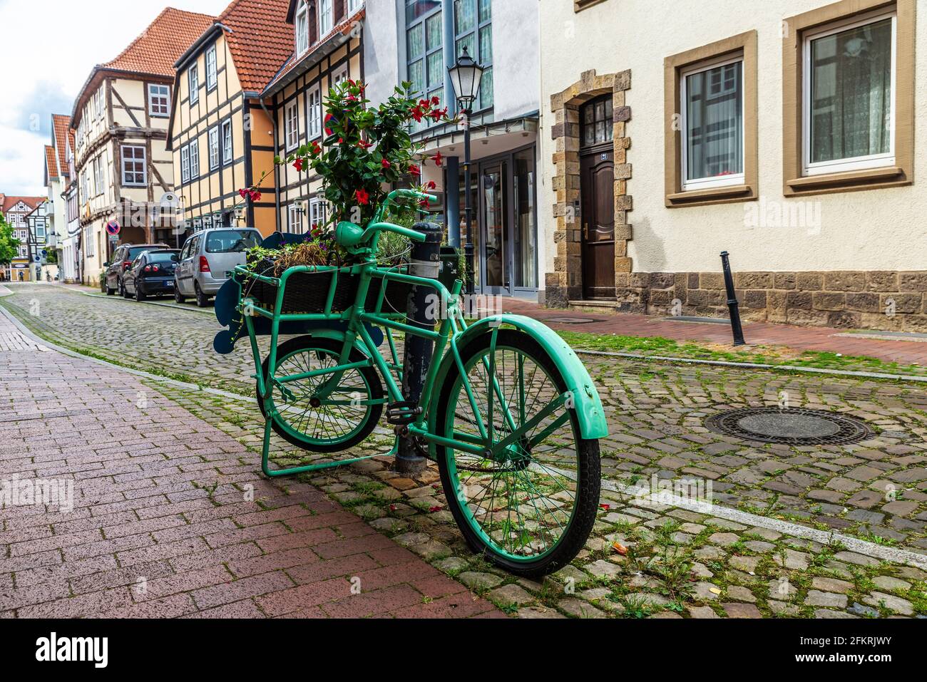 Altes grünes Retro-Fahrrad auf einer Straße mit mittelalterlichen Häusern in der Altstadt von Hameln, Niedersachsen, Deutschland geparkt Stockfoto