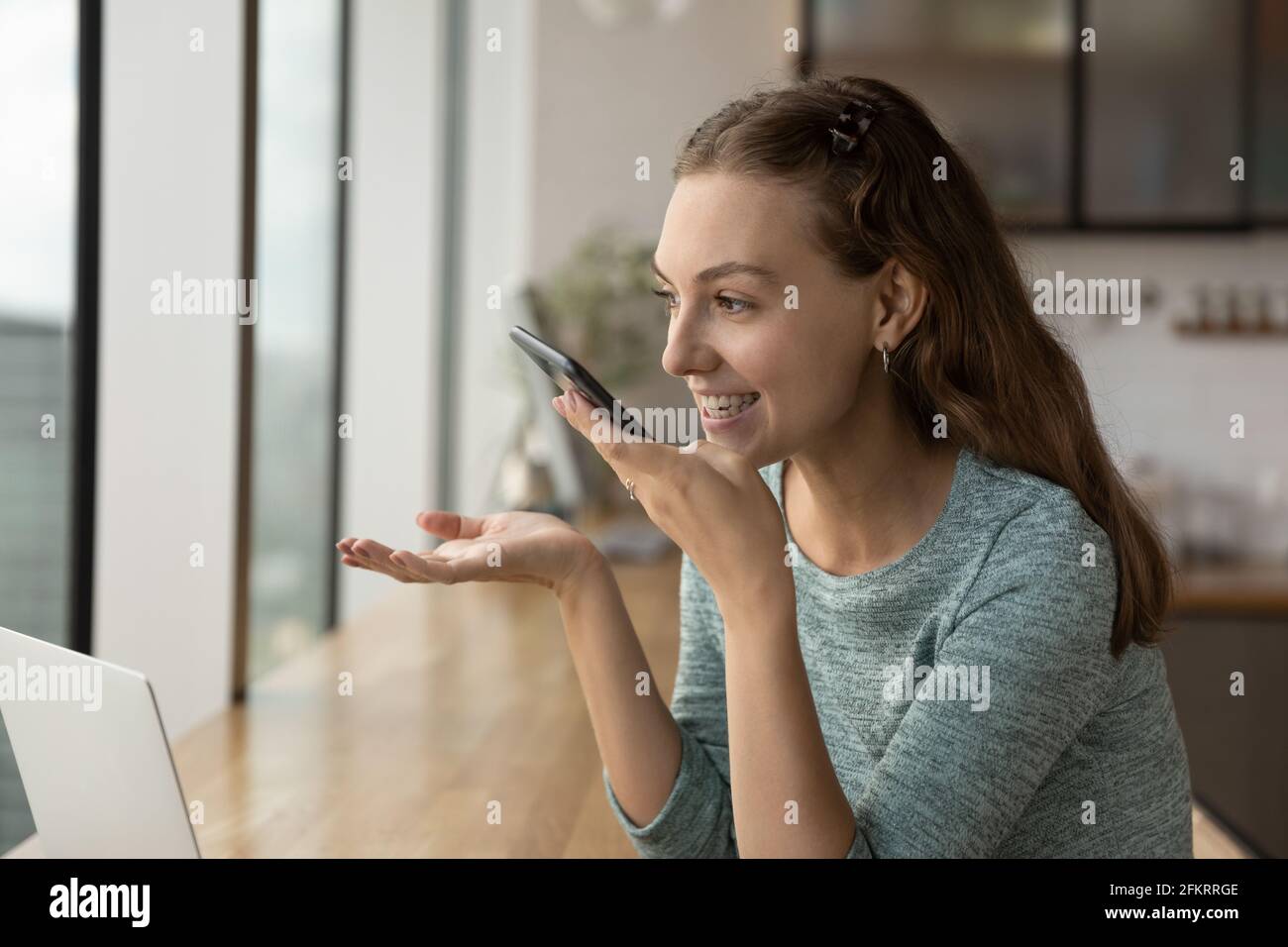 Lächelnde Frau spricht über Lautsprecher auf dem Handy Stockfoto