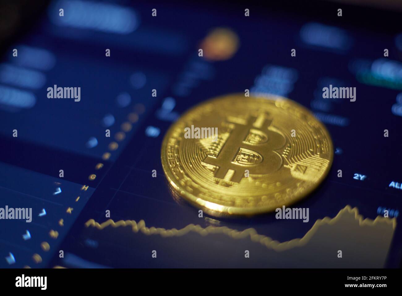Die Goldbitcoin-Münze liegt auf dem Tablet-Bildschirm, der Cha zeigt Stockfoto