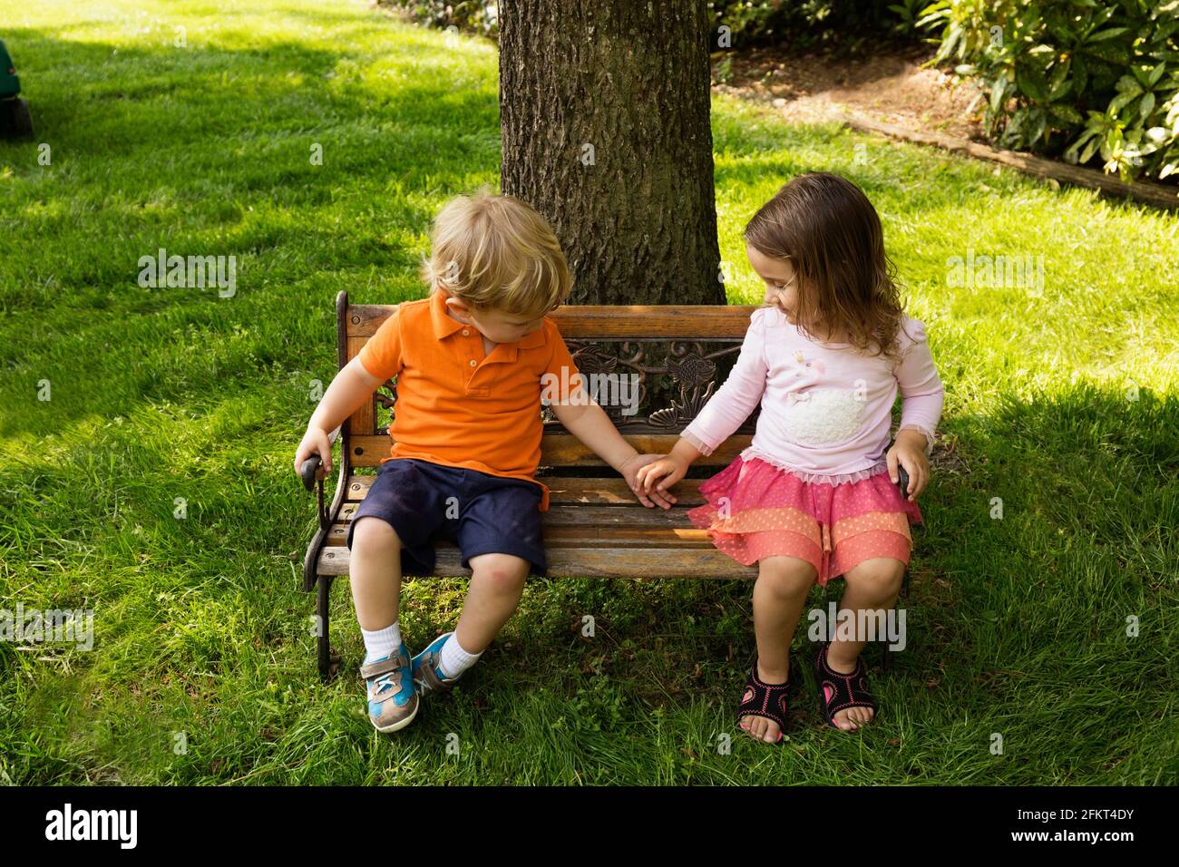 Männlichen und weiblichen Kleinkind Freunde Hand in Hand auf skaliert Parkbank Stockfoto
