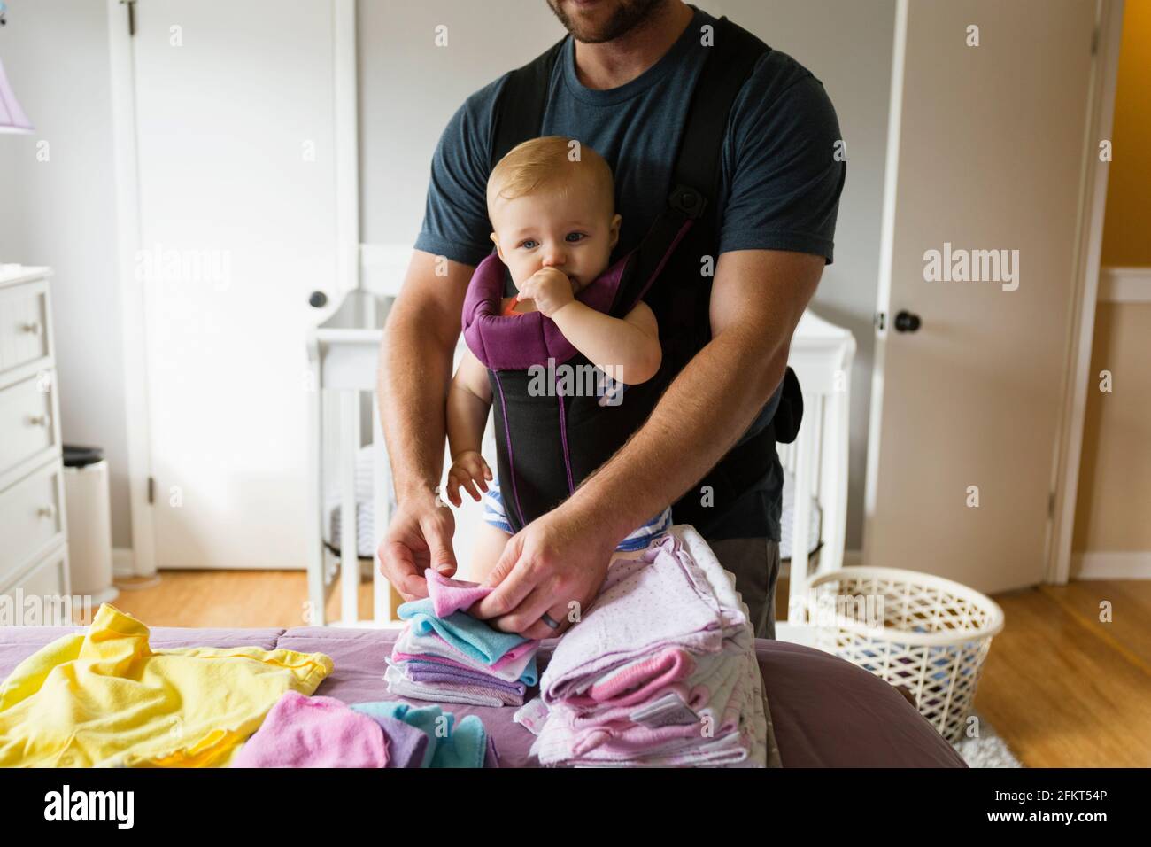 Mitte erwachsener Mann tun Hausarbeit mit Tochter im Tragetuch Stockfoto