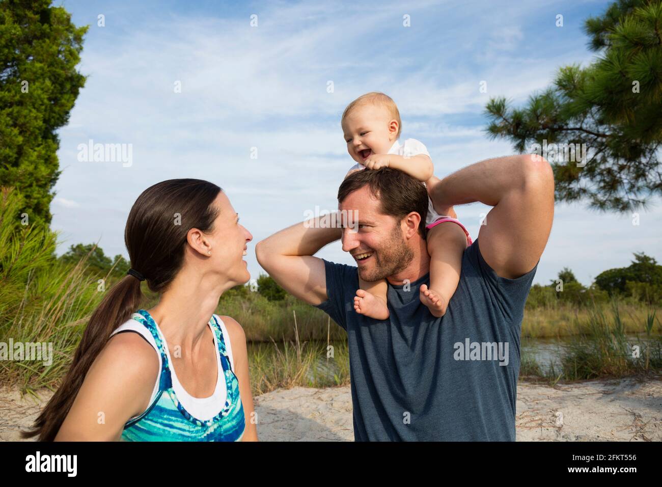 Mitte Erwachsenen Eltern mit Baby-Tochter auf mans Schultern von riverside Stockfoto