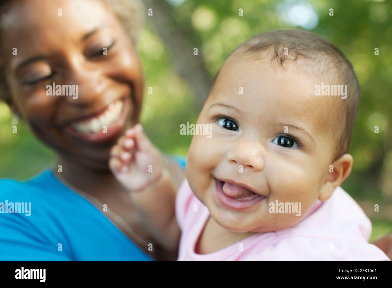 Kopf und Schultern der Mutter halten Babymädchen Blick auf die Kamera zu Lächeln Stockfoto