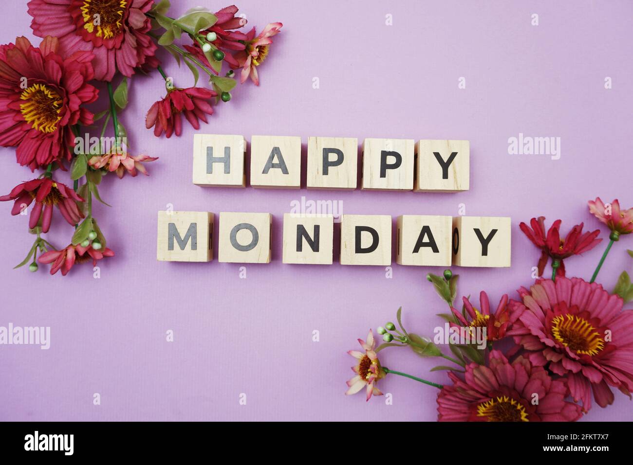 Happy Monday Buchstaben mit Blumendekoration von oben auf lila Hintergrund Stockfoto