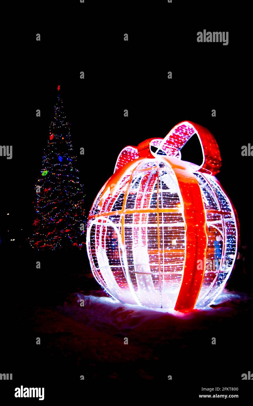 Dekoration Weihnachten in der Nacht Winterstadt - Kegel Kunstfichte und glühende Kugel mit Schleife. Stockfoto