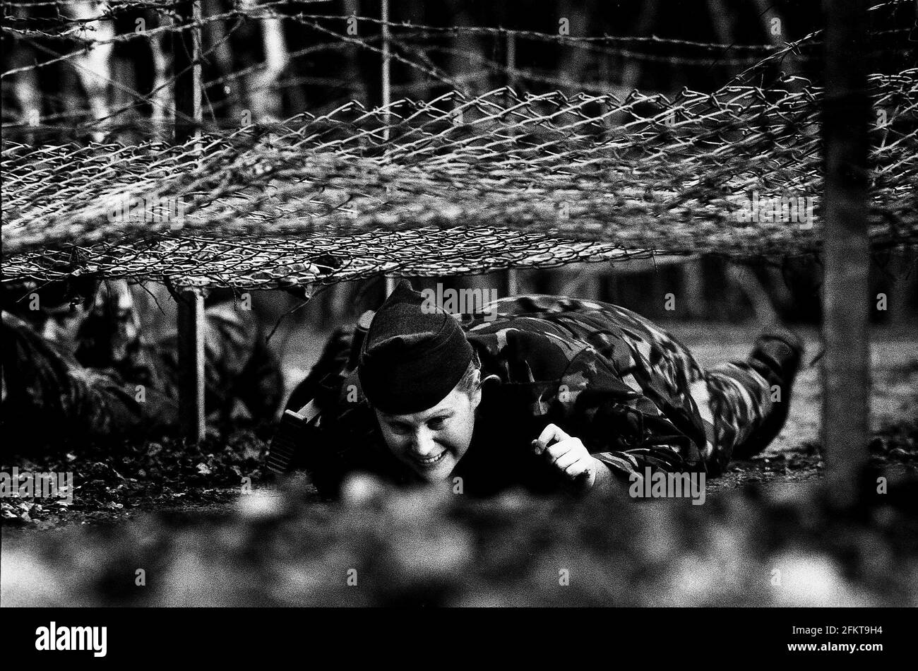 Die Soldatin der Territorialarmee kriecht unter dem Netz Ein Sturmkurs Dbase Stockfoto