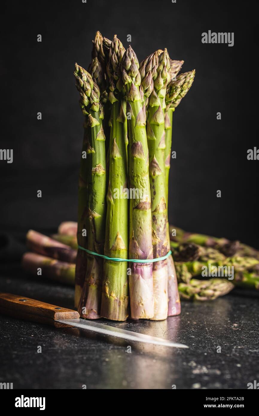 Frischer roher ungekochter grüner Spargel auf schwarzem Tisch. Stockfoto