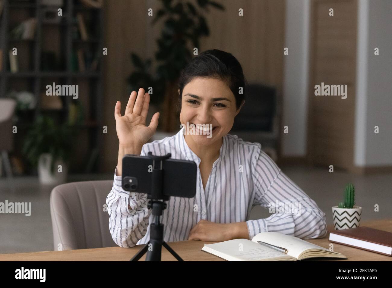 Lächelnde Inderin winkt mit der Hand auf das Smartphone und nimmt Videos auf Stockfoto
