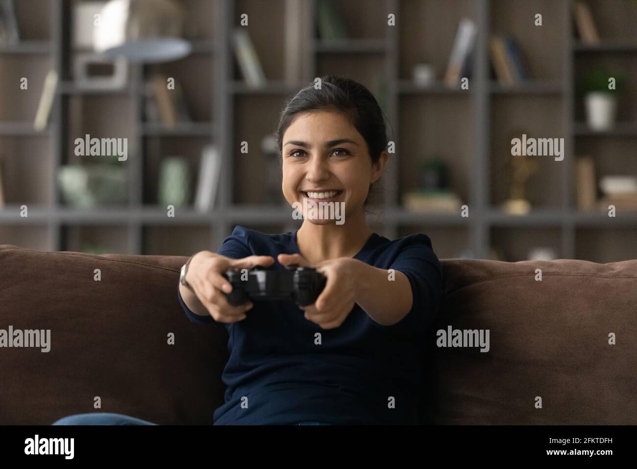 Nahaufnahme lächelnde indische Frau, die Videospiel spielt und den Controller hält Stockfoto