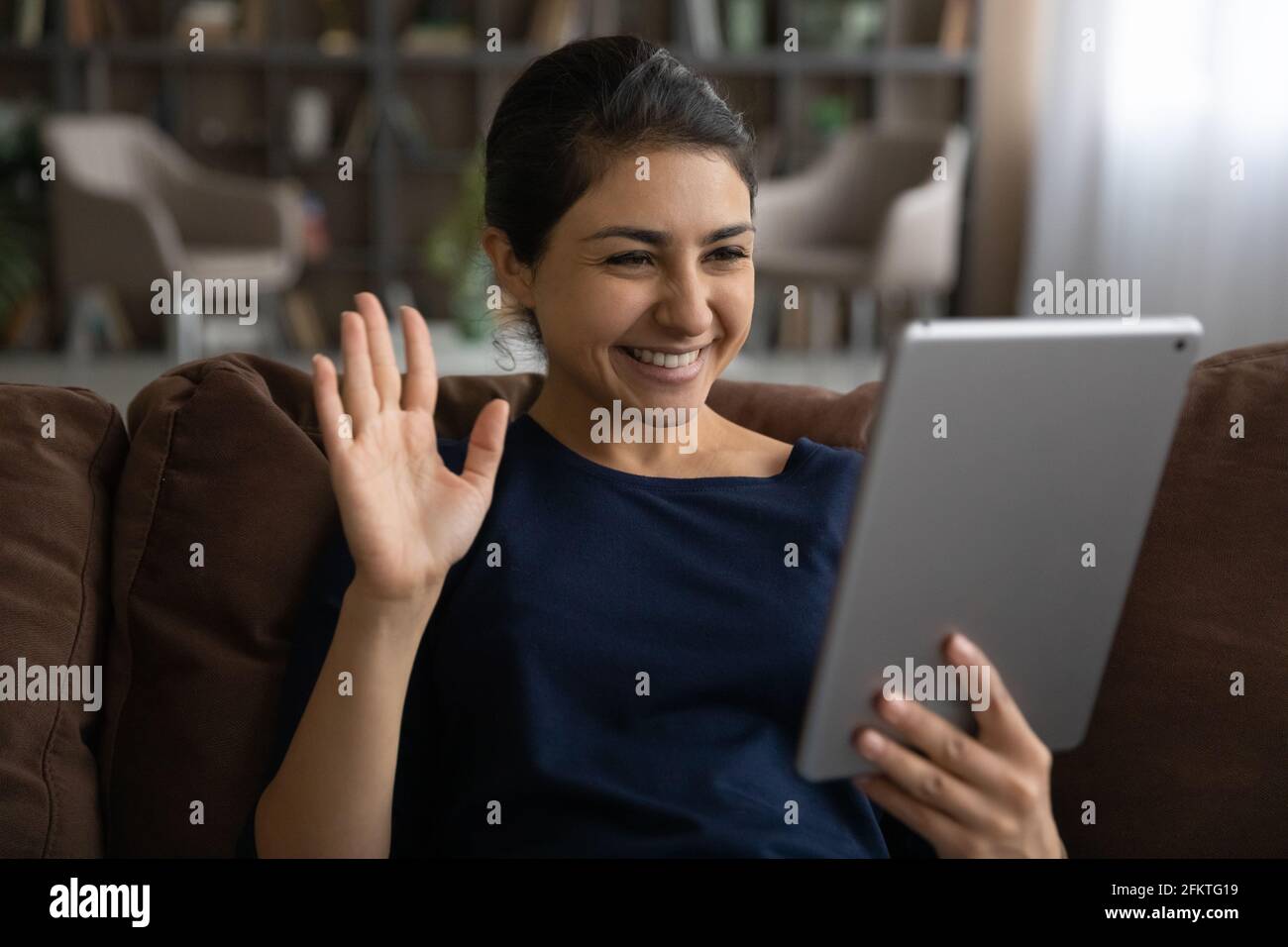 Nahaufnahme lächelnde indische Frau winkt Hand, mit Tablet Stockfoto
