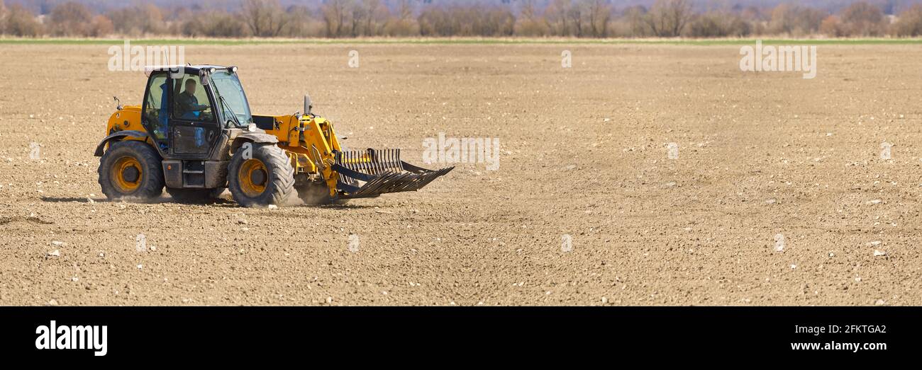 Frühjahrsarbeit auf dem Bauernhof. Landwirt im Traktor, der das Feld für die Aussaat vorbereitet. Ackerland und Traktor Stockfoto