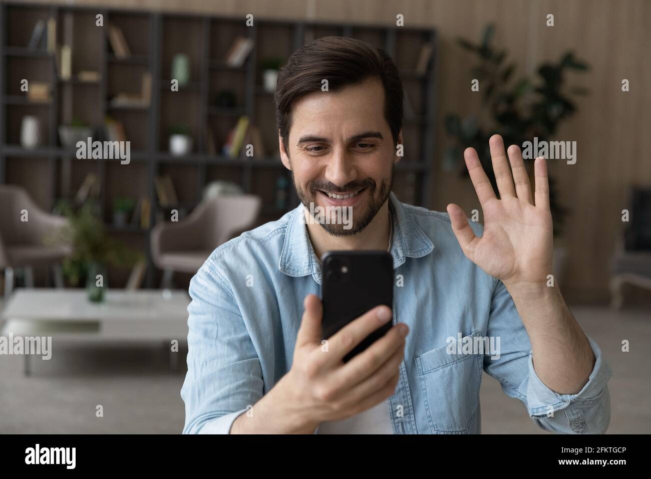 Nahaufnahme lächelnder Mann winkt Hand an Smartphone-Webcam, chattet Stockfoto