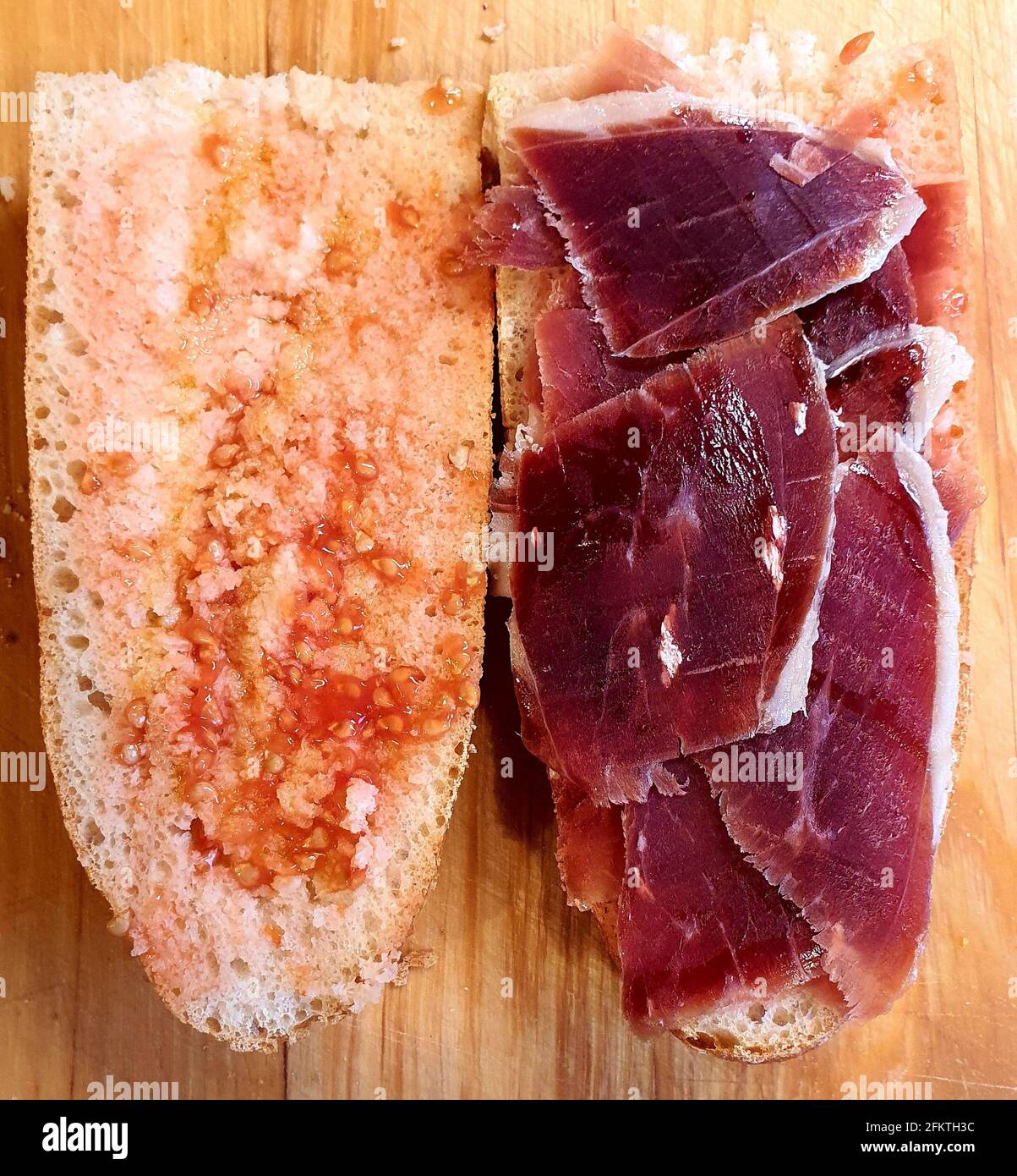Das iberische Marmelade-Sandwich ist ohne Zweifel eines der besten gastronomischen Genüsse, die es gibt. Die Tomate auf beide Scheiben verteilen und mit Olive bestreichen Stockfoto