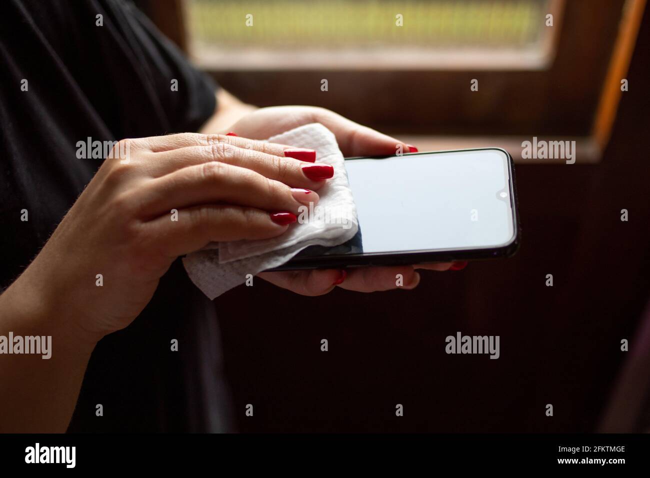 Weibliche Hände wischen Handy-Gadget mit Desinfektionsmittel nassen Tuch. Stockfoto