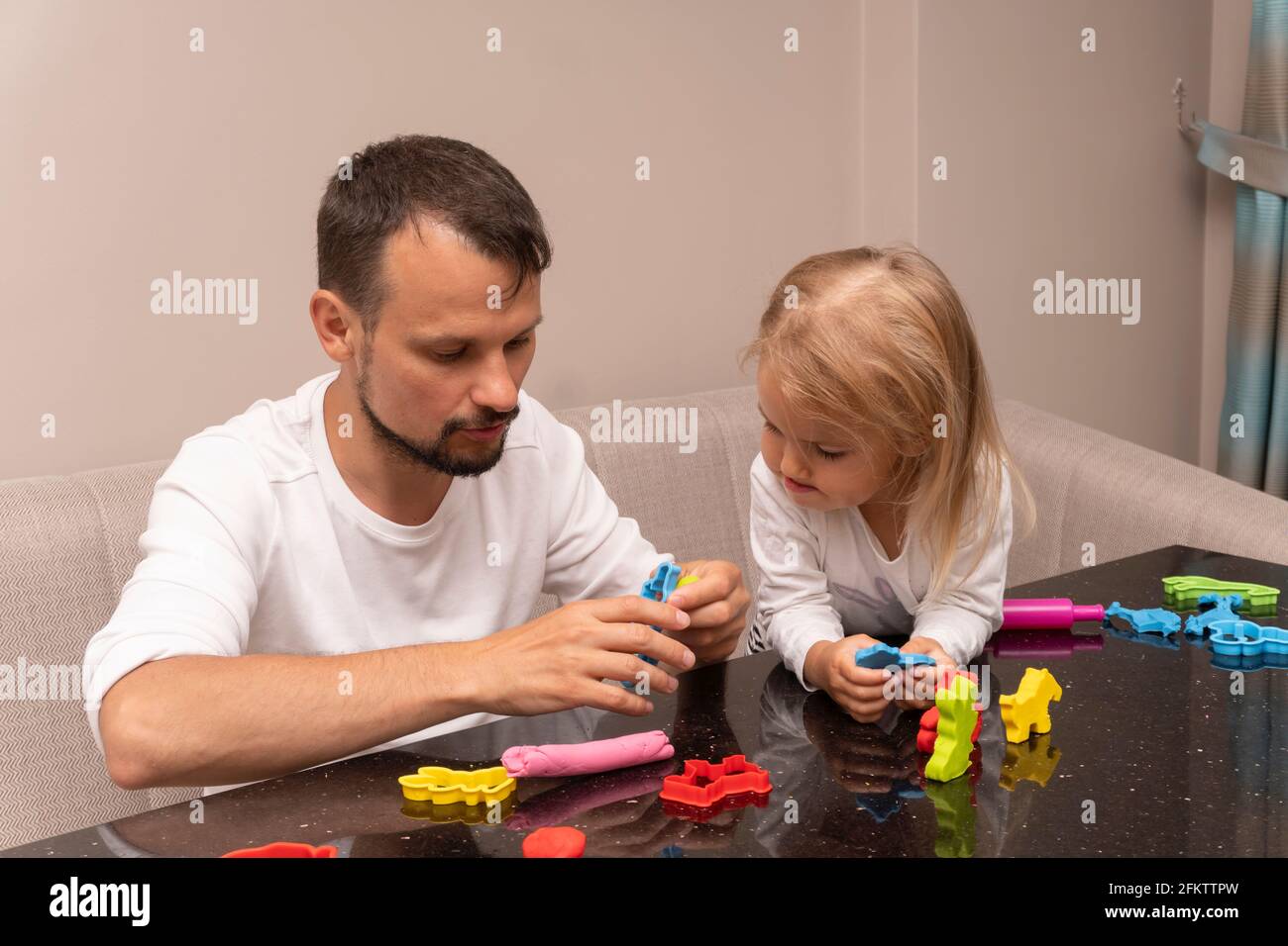 Papa lernt Tochter, wie man Tiere aus Spielteig macht Stockfoto