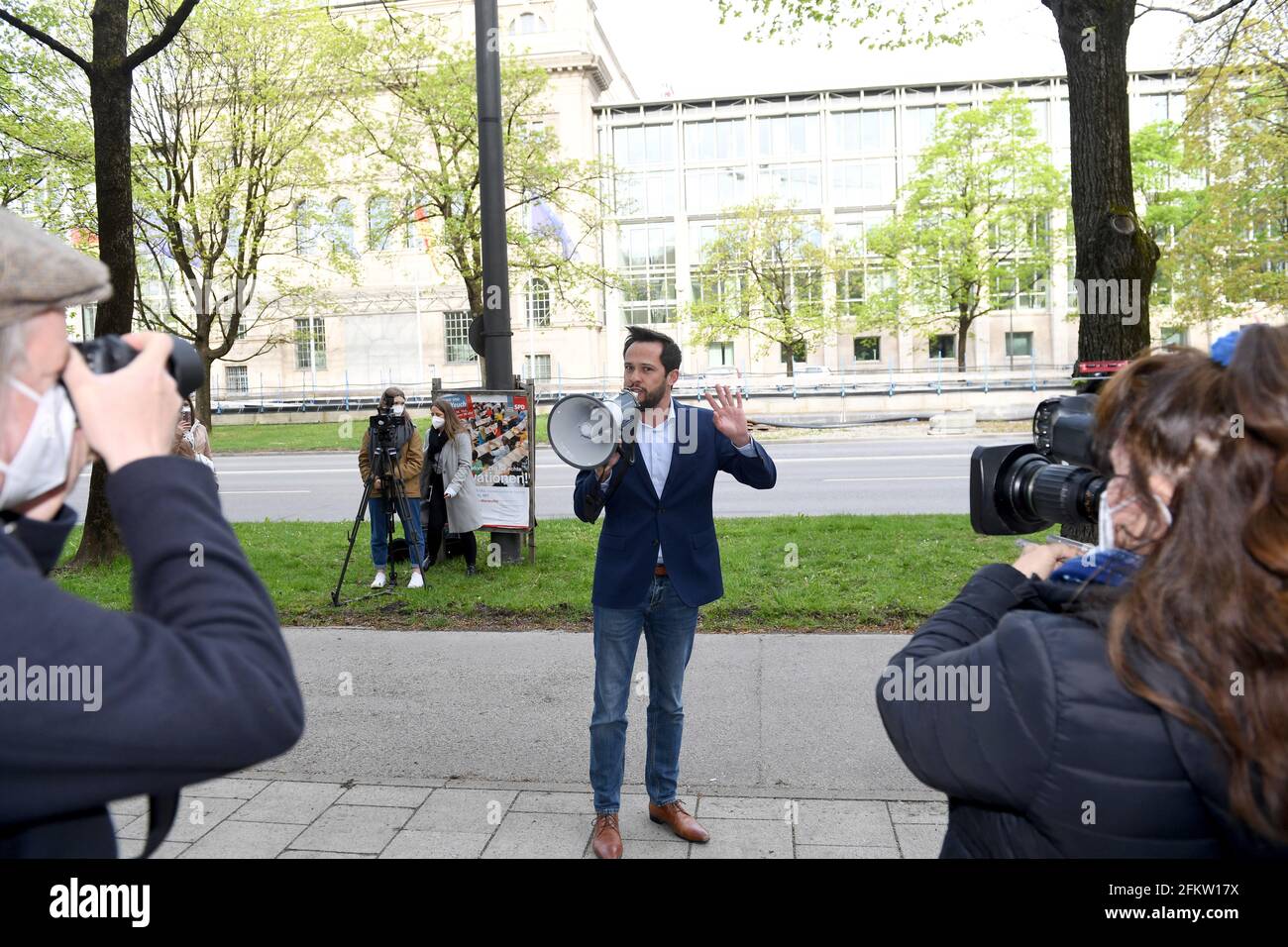 München, Deutschland. Mai 2021. Martin Hagen (FDP), Fraktionschef im Bayerischen landtag, spricht während des #LasstunsÖffnen-Protestes vor der Bayerischen Staatskanzlei in ein Megaphon, während er von der Presse fotografiert und gefilmt wird. Vertreter bayerischer Initiativen protestieren am Tag der Kabinettssitzung vor der Staatskanzlei in München unter dem Motto "Lösungen statt Verbote, Mut statt Angst und Freiheit statt Einsamkeit. Quelle: Felix Hörhager/dpa/Alamy Live News Stockfoto