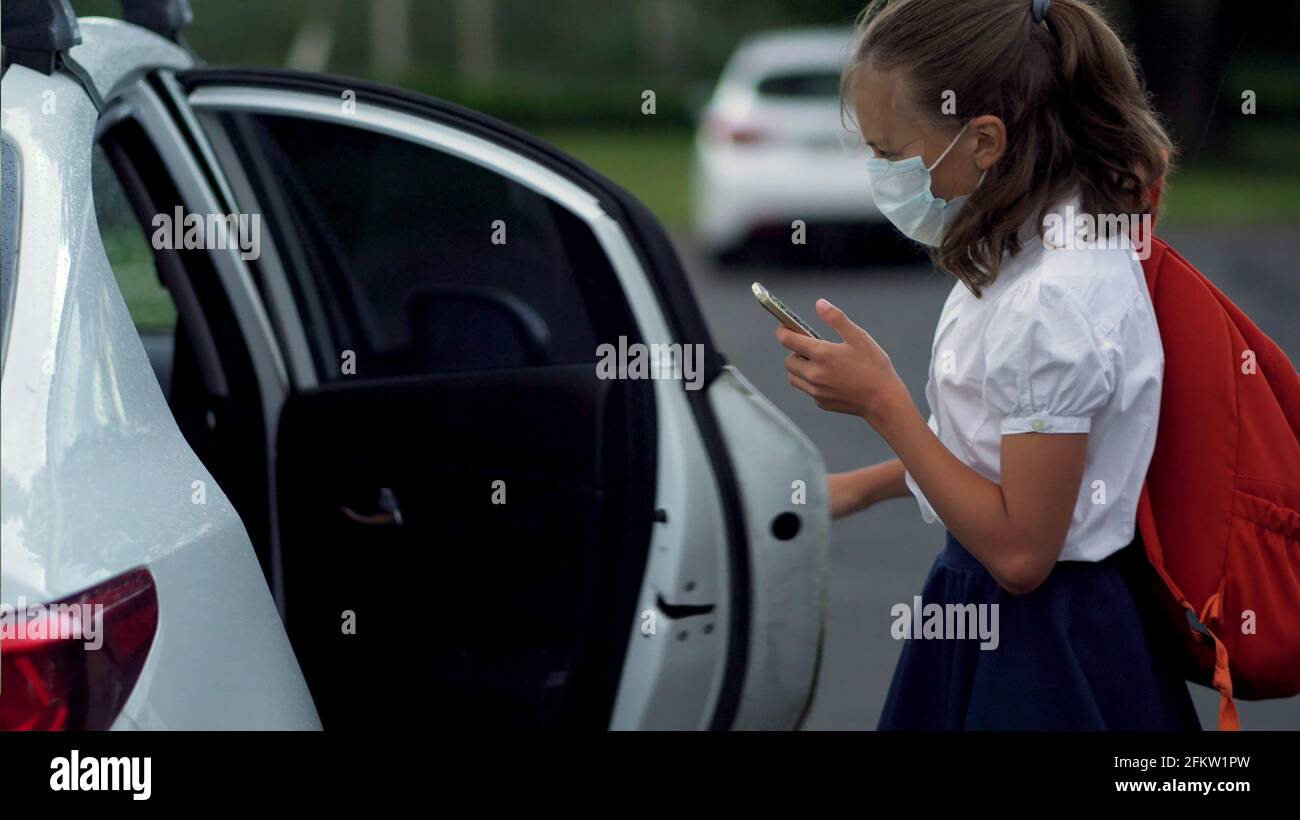 Nette Schüler mit Smartphones an der Grundschule. Junge und Mädchen in Sicherheitsmasken mit Gadgets in den Händen. Stockfoto