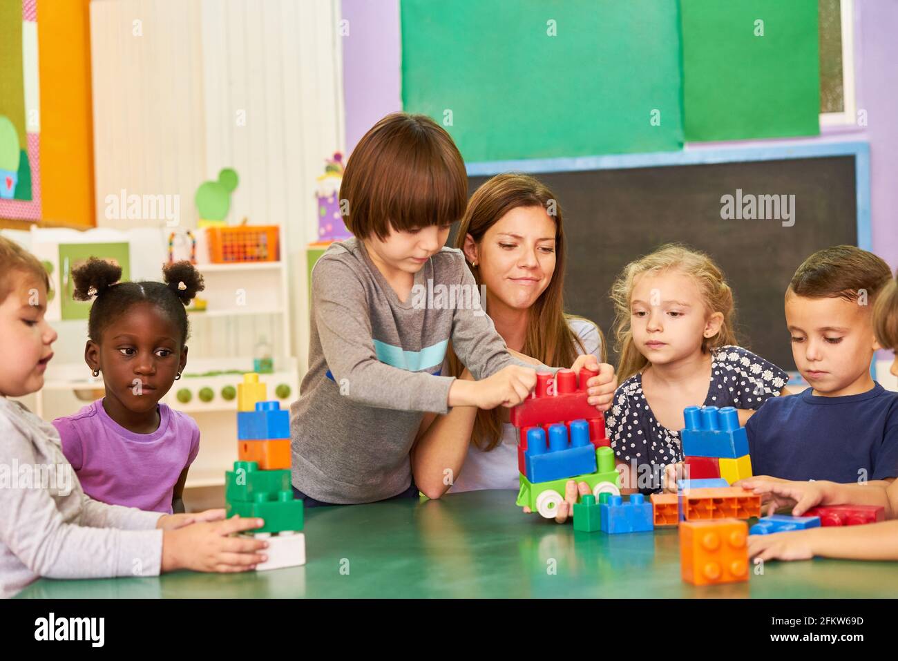 Gruppe von Kindern und Erzieher Gebäude mit Blöcken zusammen in Kindergarten oder Nachschulpflege Stockfoto