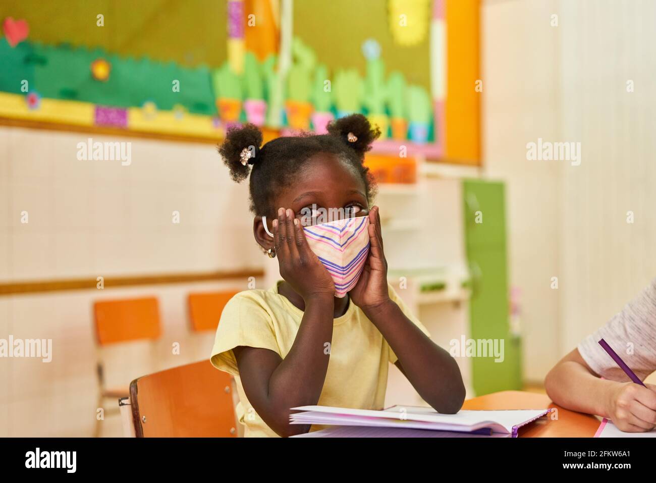 Afrikanisches Mädchen mit Schutzmaske im Kindergarten wegen Covid-19 Und Coronavirus Stockfoto