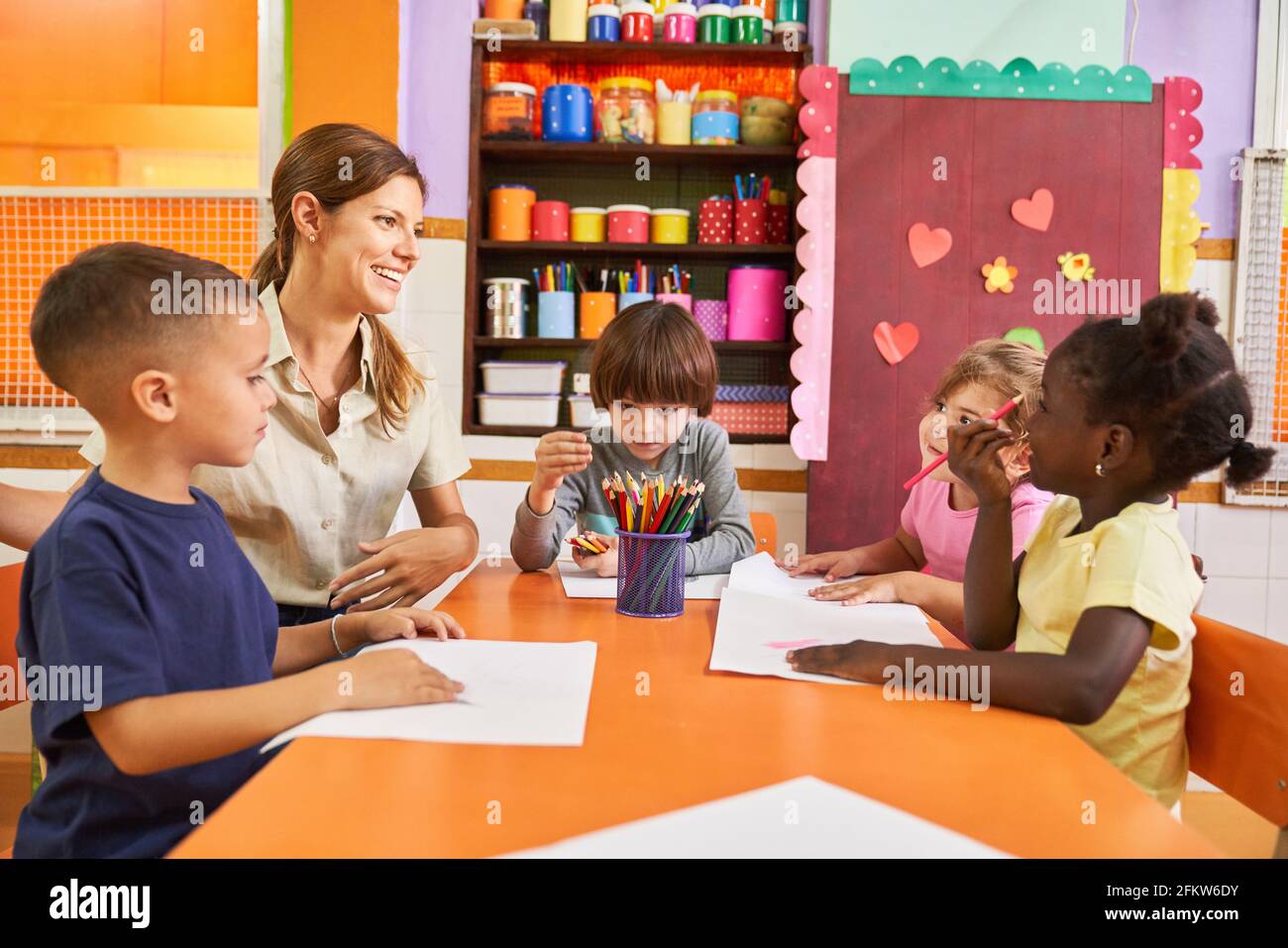 Pädagoge und Gruppe von Kindern in einem kreativen Malkurs In einem internationalen Kindergarten oder in einem nachschulischen Pflegezentrum Stockfoto