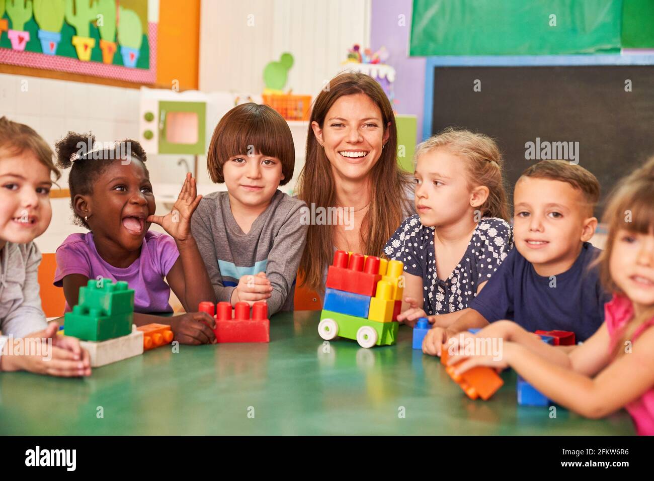 Glückliche Kinder in der Vorschule oder im internationalen Kindergarten mit einem Kindergärtnerin Stockfoto
