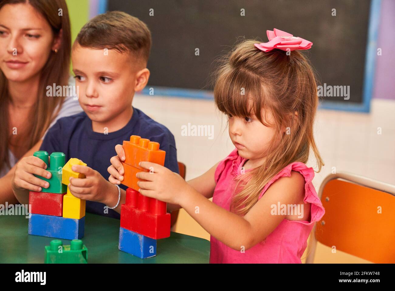 Kleines Mädchen spielt mit bunten Bausteinen im Kindergarten oder Vorschule Stockfoto