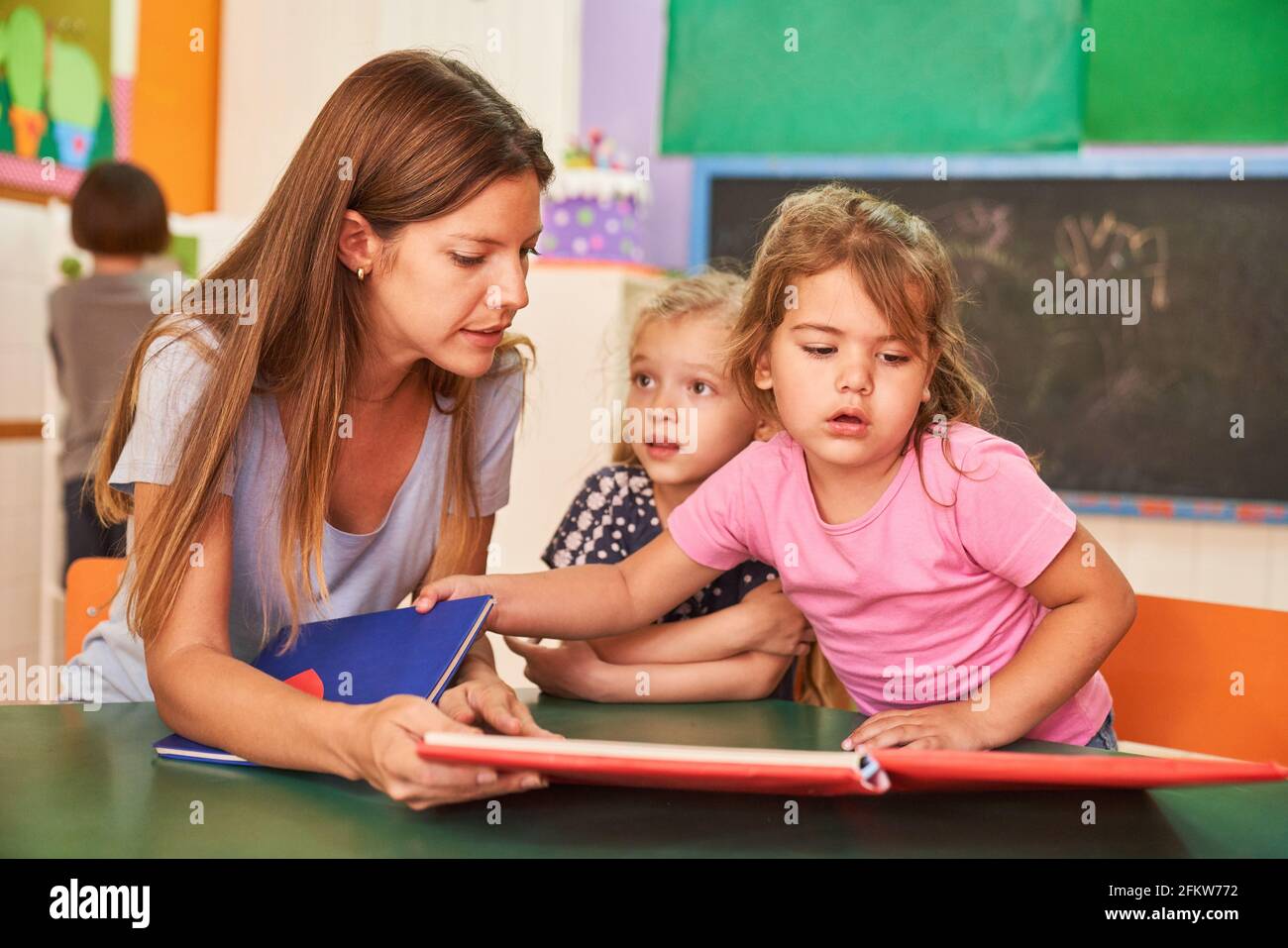 Erzieherin oder Lehrerin mit Kindern, die im Kindergarten lesen lernen Oder im Vorschulalter Stockfoto