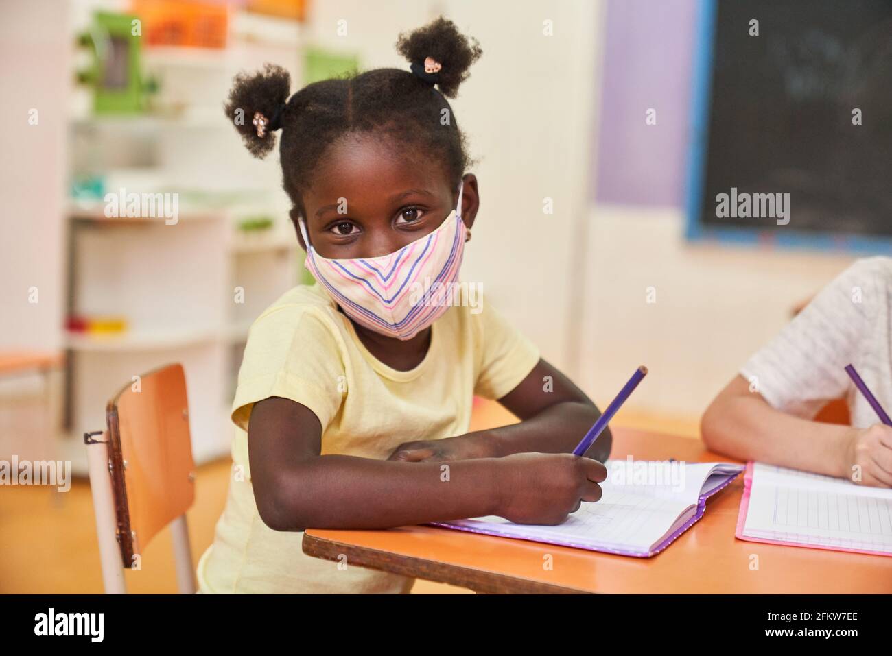 Afrikanisches Mädchen mit Schutzmaske wegen Covid-19 in der Vorschule Oder der Grundschule Stockfoto
