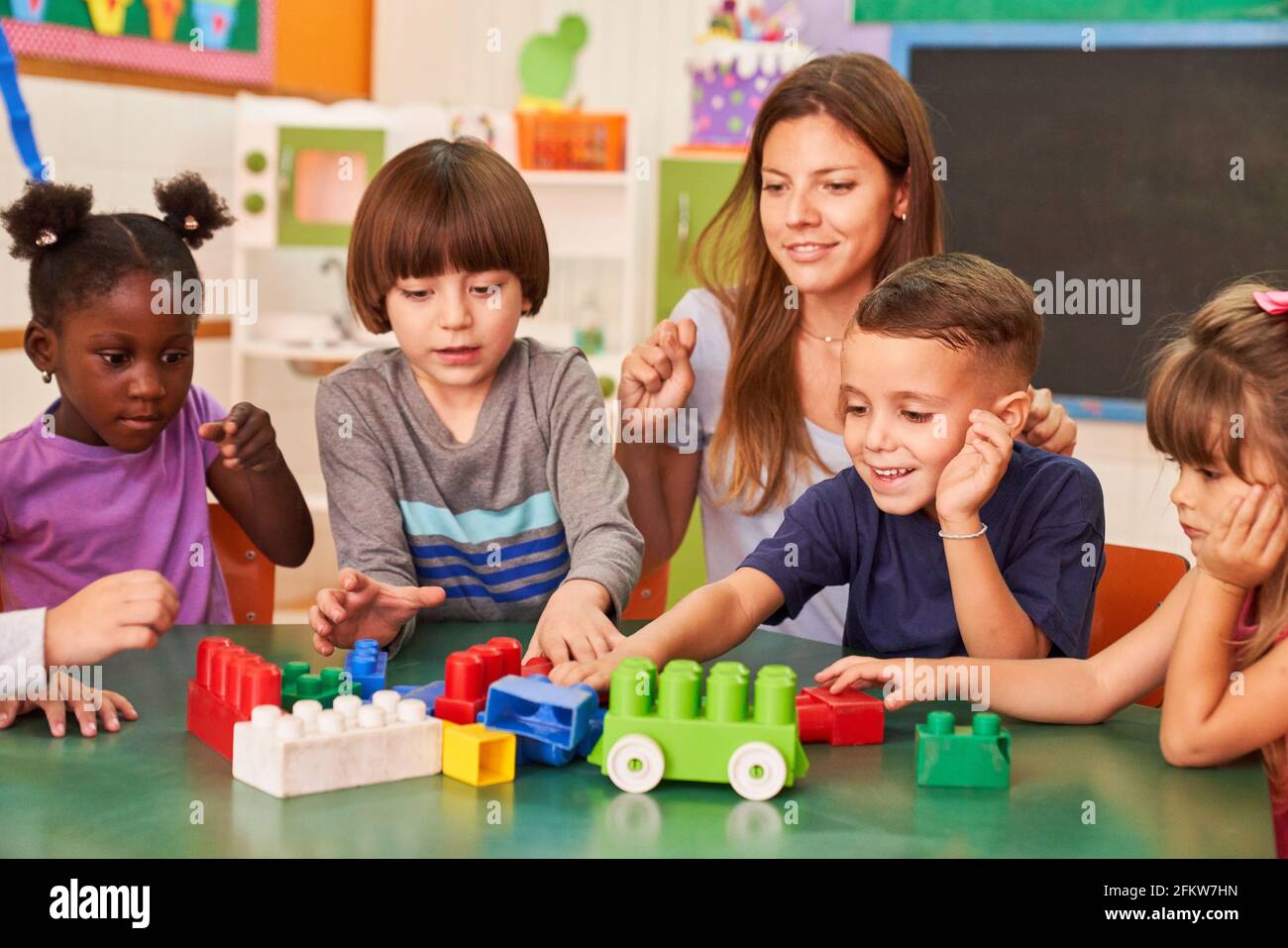 Kinder spielen in der Nachschulpflege mit bunten Bausteinen Zentrum oder Kindergarten unter der Leitung eines Erziehers Stockfoto